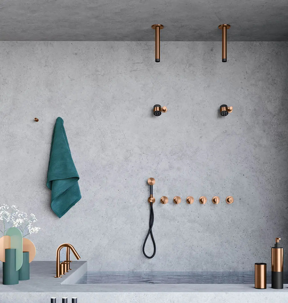 Soffione Ø 70 con 7 ugelli soft-flow e raccordo a parete con snodo - SWN3  Soffione a soffitto Bud con getto laminare splash-free - SSN2 In abbinamento a rubinetteria serie Kira e accessori tondi, tutto in finitura bronzo spazzolato PVD