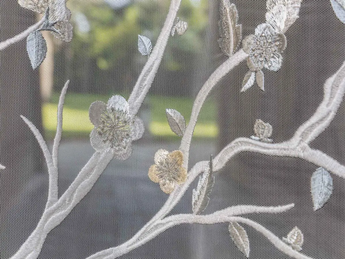 Fiori di ciliegio finemente ricamati incorniciano lo spazio, creando affascinanti atmosfere orientali.