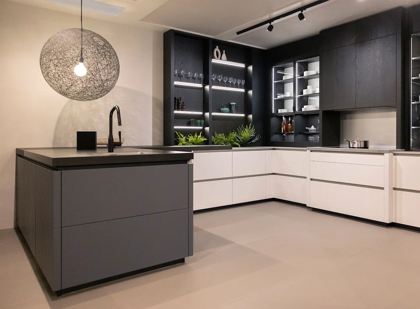 View of a kitchen with matt white cabinets and a dark grey peninsula. The wall units are in dark wood.