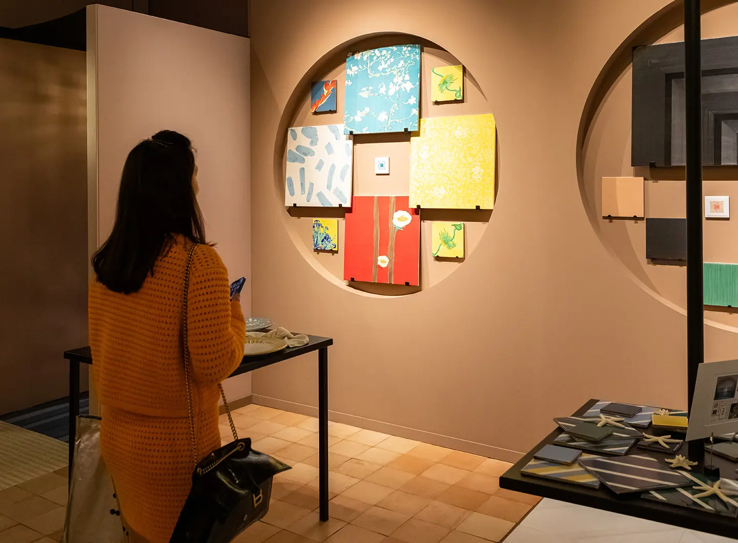 Woman from behind looking at square majolica compositions hanging on the wall