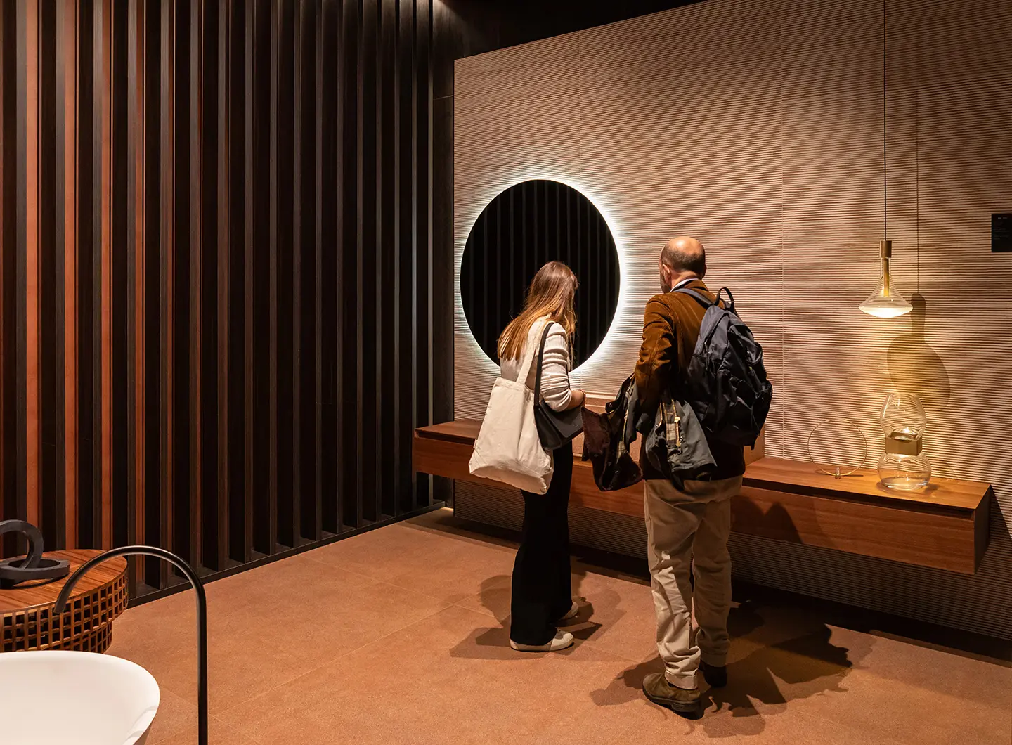 Two people in front of a bathroom cabinet hanging on a wall covered with ceramic panels