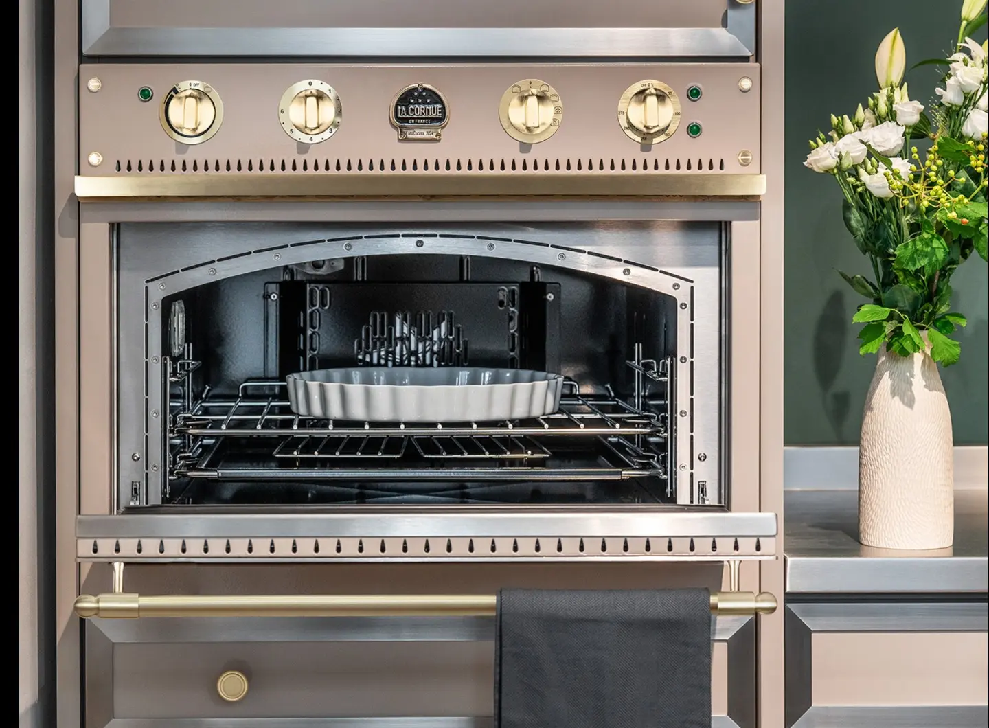 Forno incorporato 90 Grège, finiture in acciaio inox lucido, ornamentie portasciugamani in ottone satinato.