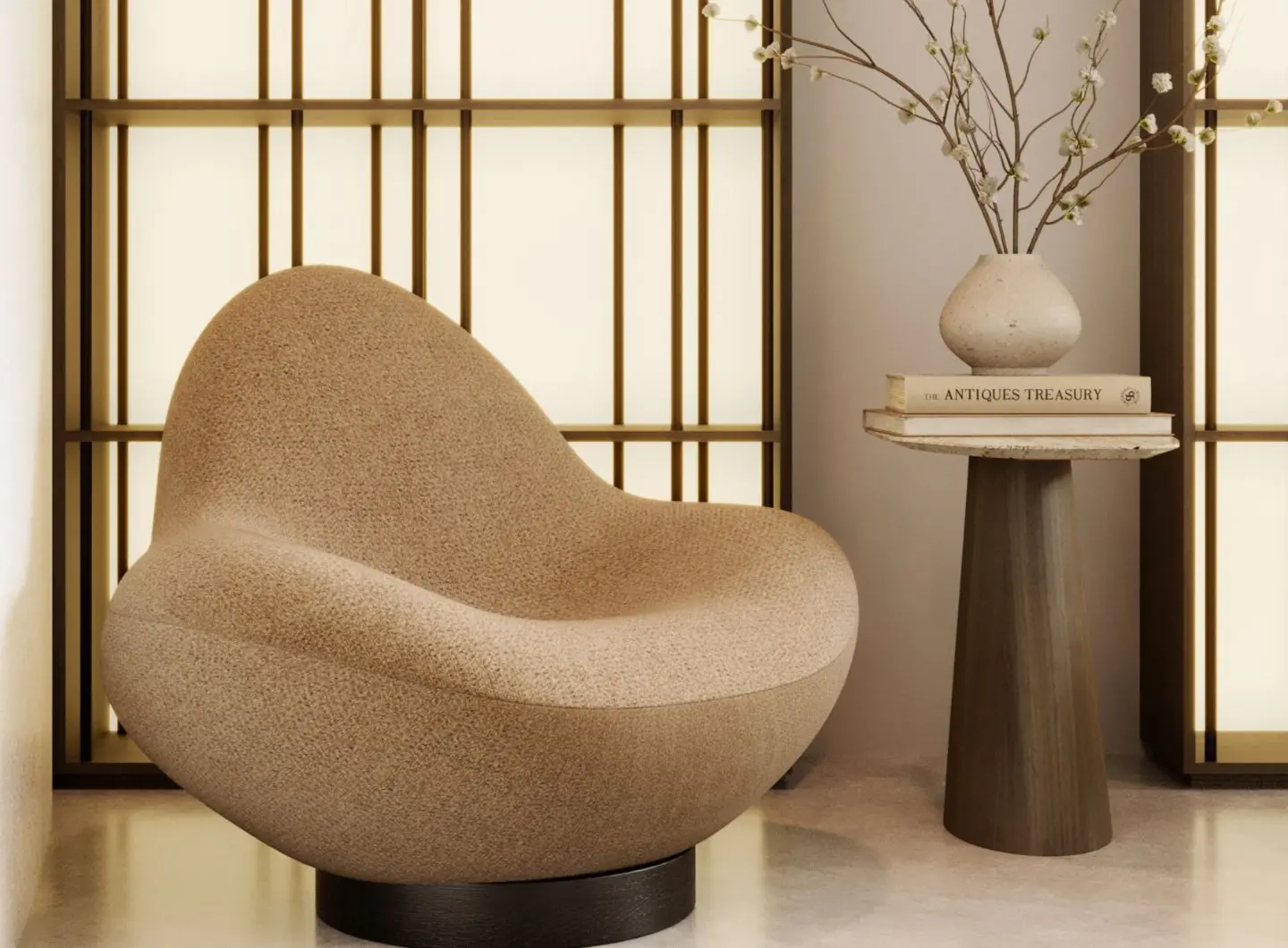 La poltrona Stone, rivestita in tessuto beige testurizzato e caratterizzata da morbide linee arrotondate, è collocata accanto a un tavolino su cui sono appoggiati dei libri e un vaso di ceramica con dei rami, in un ambiente caldo e minimalista.