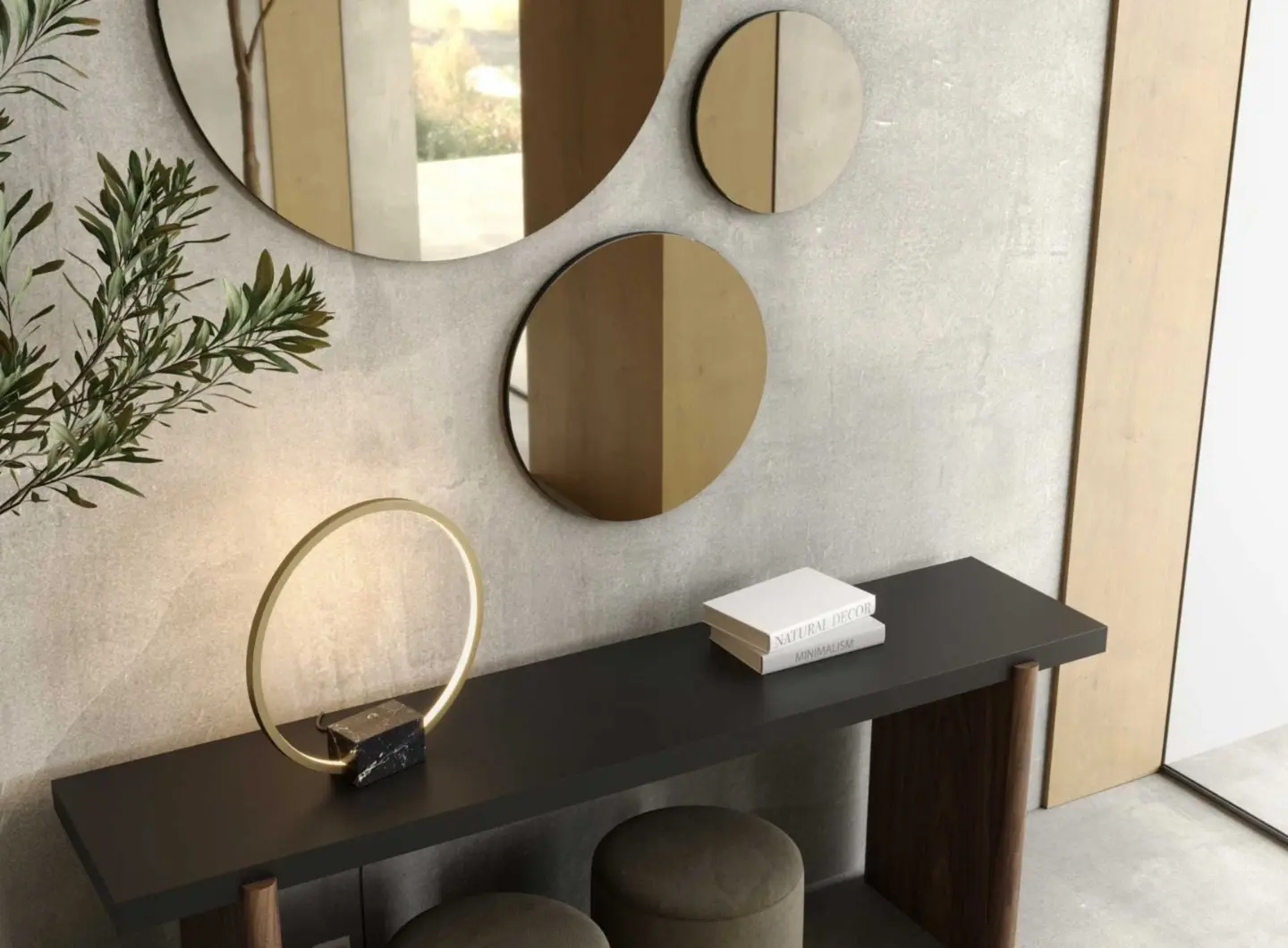 Lo specchio Circle appare come parte di una composizione asimmetrica di specchi rotondi montati su una parete testurizzata sopra una consolle minimalista con lampada circolare, libri impilati e sgabelli imbottiti, creando un insieme moderno e caldo in cui riflessi e luce soffusa aggiungono profondità e armonia allo spazio.