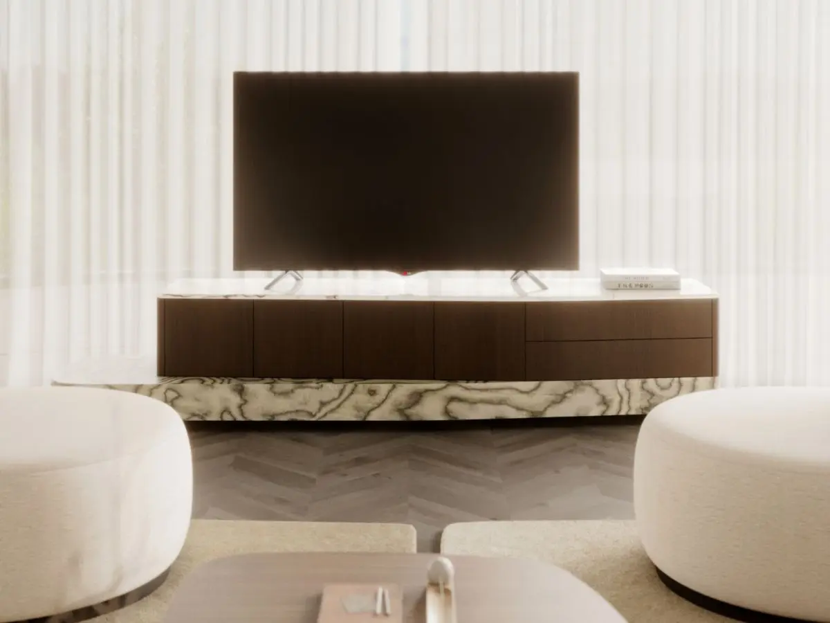 Il mobile TV Stone si presenta come un lungo mobile multimediale in microcemento con piano in travertino, su cui è appoggiato un grande televisore, con libri e oggetti decorativi disposti sulla superficie, collocato in un luminoso soggiorno inondato da una morbida luce naturale e arredato con mobili dai toni neutri.