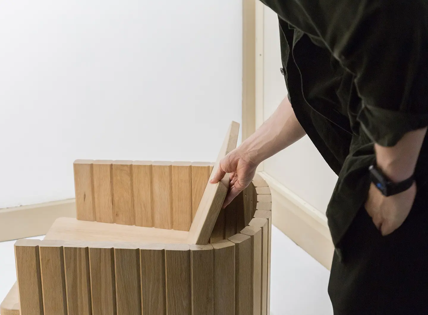 visitatore che osserva una poltroncina in legno all'interno di uno stand